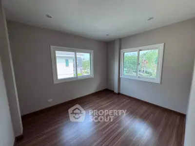 Spacious empty room with large windows and wooden flooring, perfect for customization.