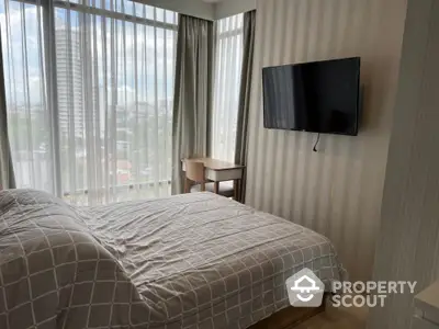 Modern bedroom with large windows and wall-mounted TV in a high-rise apartment.