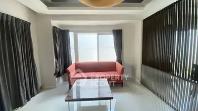 Modern living room with red sofa and large windows, featuring elegant curtains and a sleek coffee table.