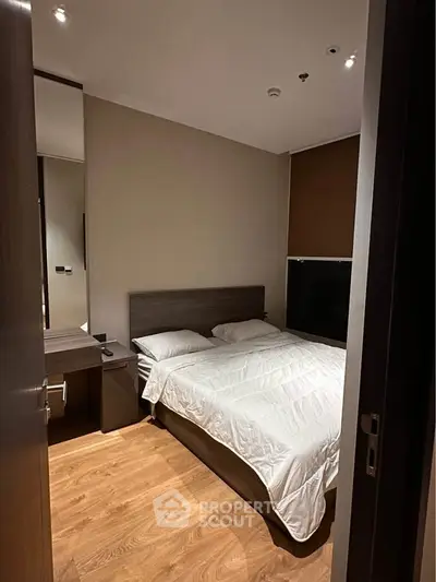 Cozy modern bedroom with wooden flooring and sleek furniture design.