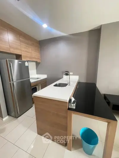 Modern kitchen with sleek design, featuring stainless steel fridge and elegant countertops.
