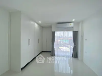 Bright and spacious bedroom with large windows and built-in wardrobe, offering a serene city view.