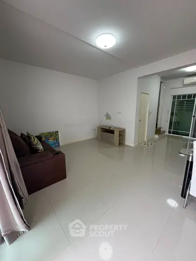 Spacious living room with modern tile flooring and natural light.