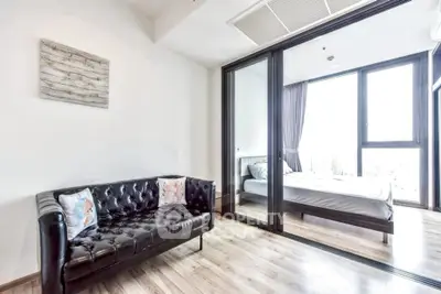Modern apartment with sleek black leather sofa and bright bedroom view.