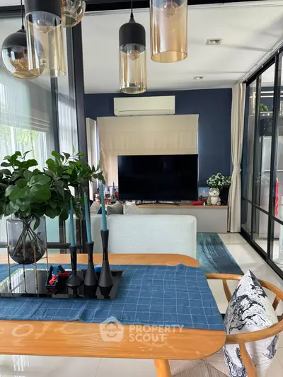 Modern living room with stylish decor and large TV, featuring elegant lighting and a cozy atmosphere.