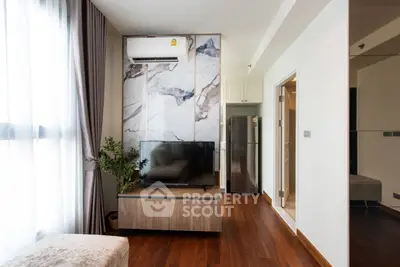 Modern living room with stylish decor and natural light, featuring a TV and air conditioning unit.