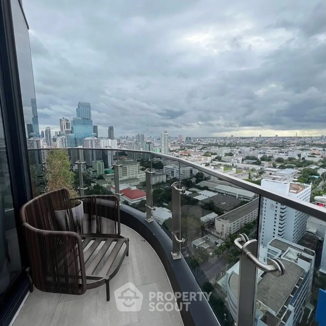 Stunning cityscape view from a modern high-rise balcony with sleek glass railing.