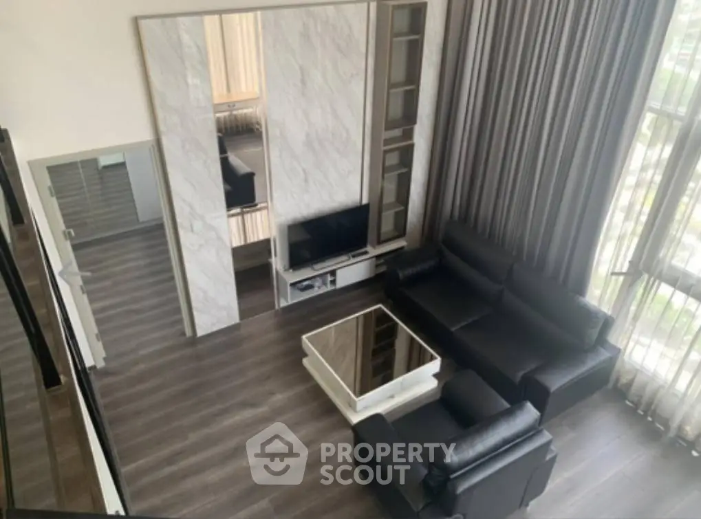Modern living room with sleek black leather sofas and large windows