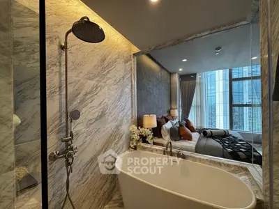 Luxurious bathroom with freestanding tub and city view from adjacent bedroom