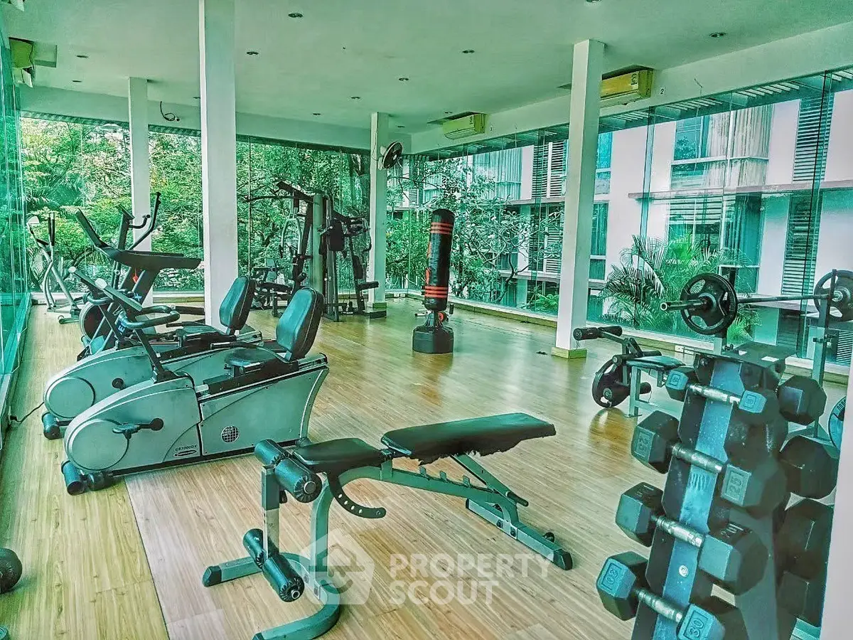 Spacious modern gym with state-of-the-art equipment and large windows offering lush garden views.