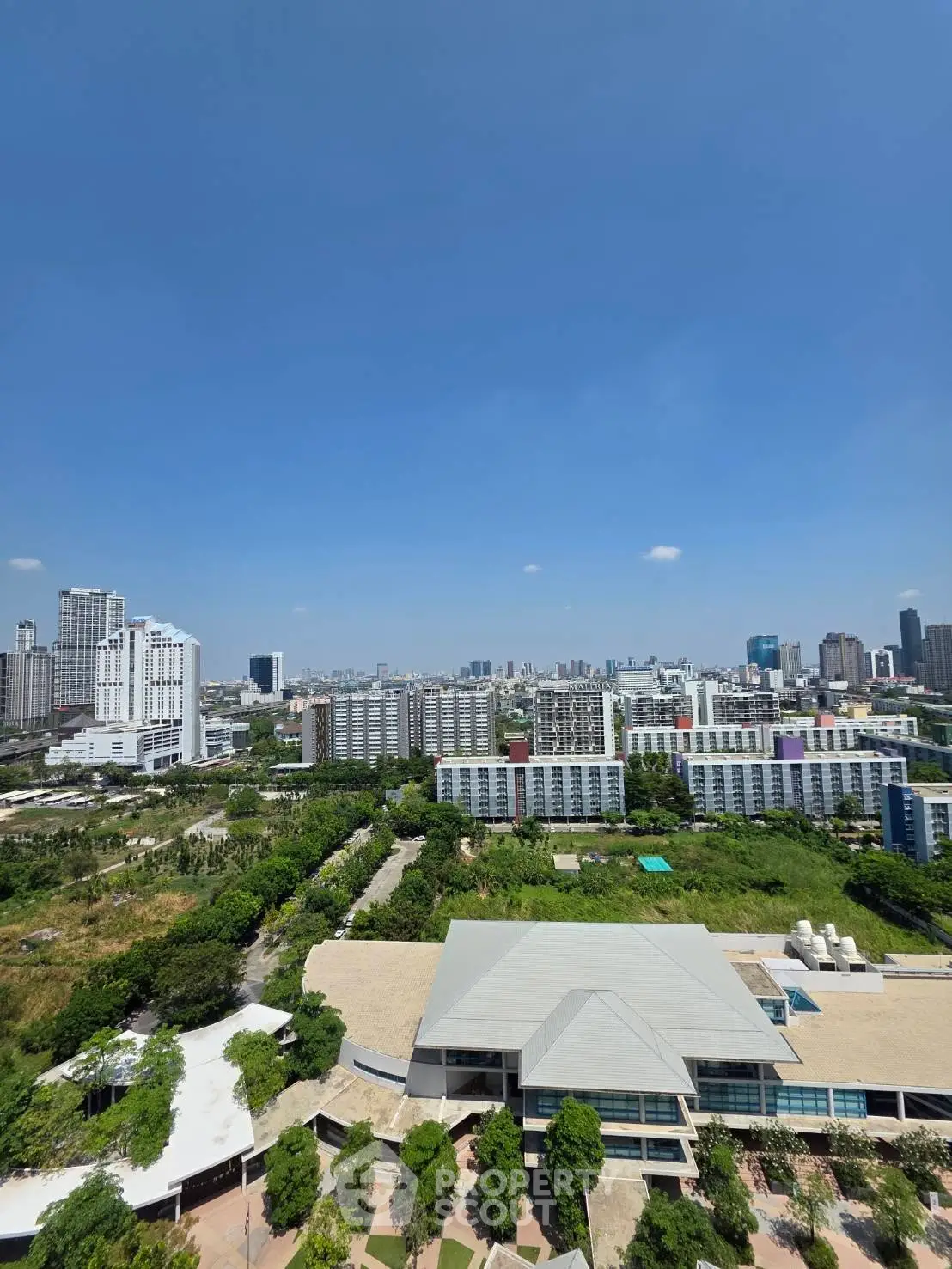 Stunning cityscape view from high-rise building showcasing urban skyline and lush greenery.