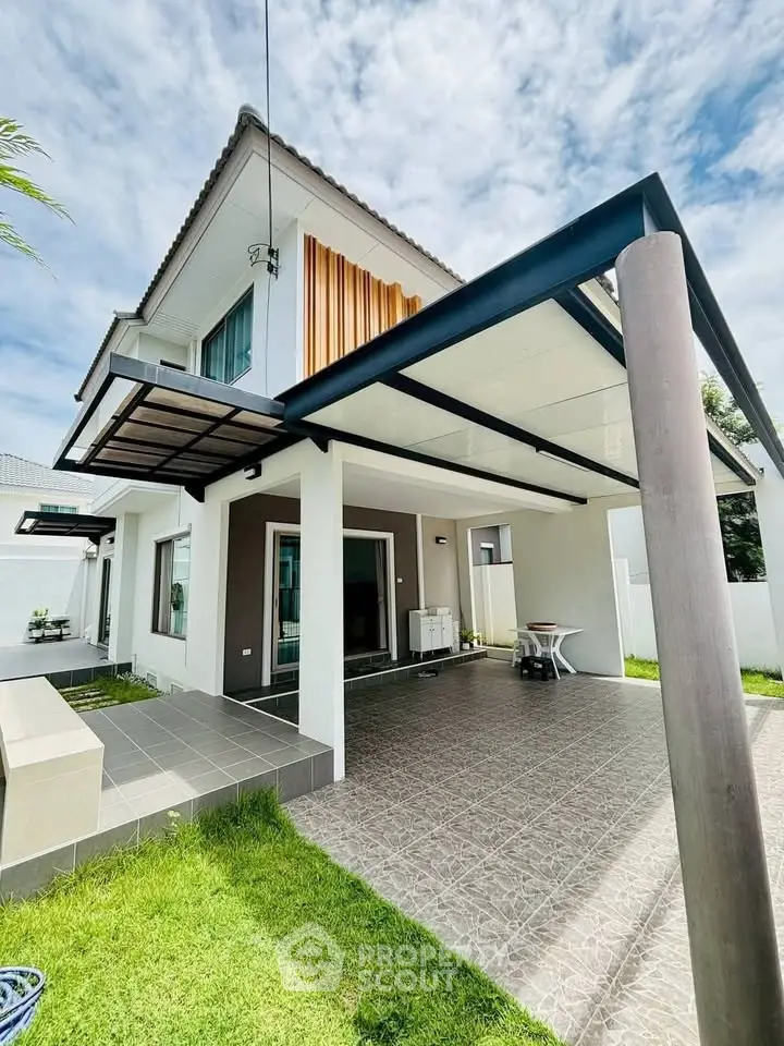 Modern two-story house with sleek design and spacious carport, surrounded by lush greenery.