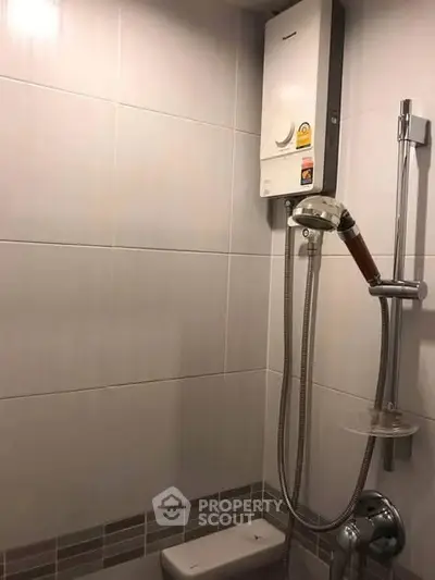 Compact bathroom with modern shower and water heater, ideal for efficient living spaces.
