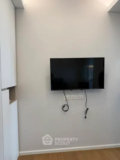 Modern living room with wall-mounted TV and sleek cabinetry, showcasing minimalist design and functionality.