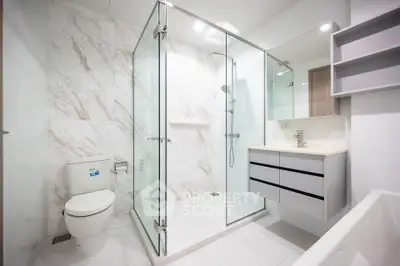 Modern bathroom with glass shower and sleek fixtures in luxury apartment.