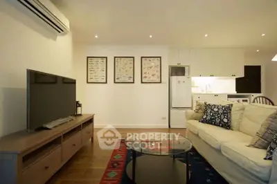 Modern living room with cozy sofa, flat-screen TV, and stylish decor in open-plan apartment.
