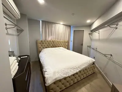 Spacious bedroom with elegant tufted bed and ample closet space