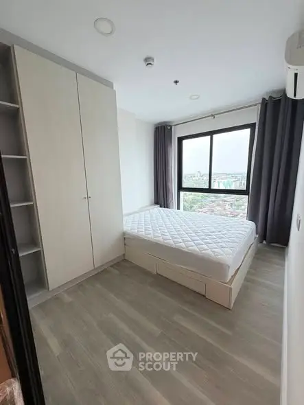 Modern bedroom with large window and city view, featuring sleek wardrobe and minimalist design.