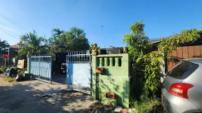 Charming residential entrance with lush greenery and secure gate in a serene neighborhood.