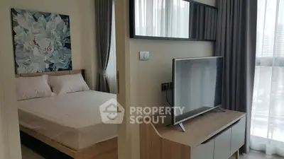 Modern bedroom with stylish decor and large TV in a bright apartment.
