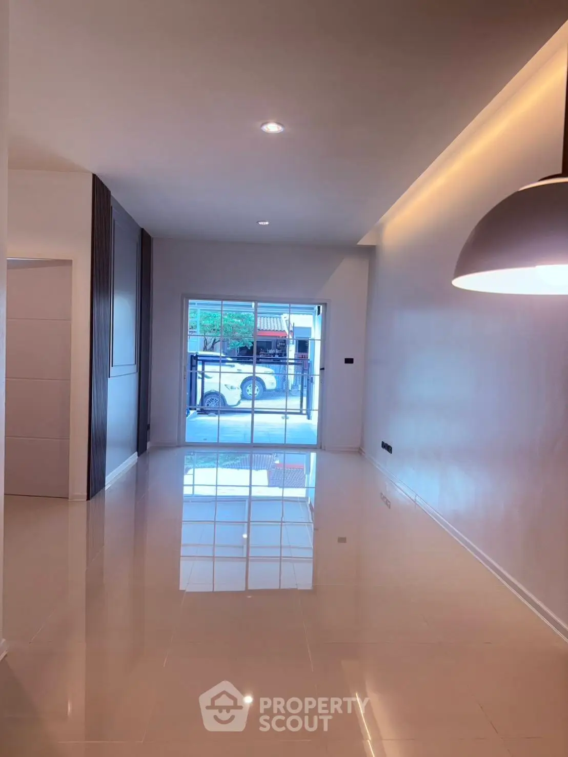 Spacious modern living room with glossy tile flooring and large window view.
