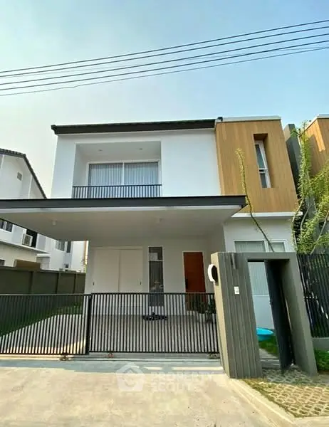 Modern two-story house with sleek design and gated entrance in suburban neighborhood.