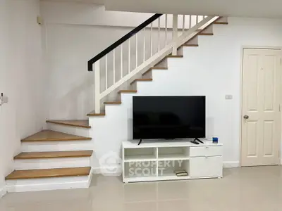 Modern living room with sleek staircase and large flat-screen TV, perfect for contemporary living.