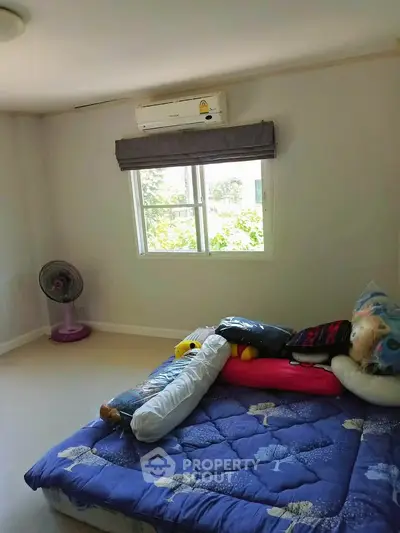 Cozy bedroom with air conditioning and window view, featuring a comfortable bed and fan.