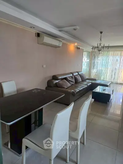 Spacious living room with modern furniture and elegant chandelier, perfect for family gatherings.