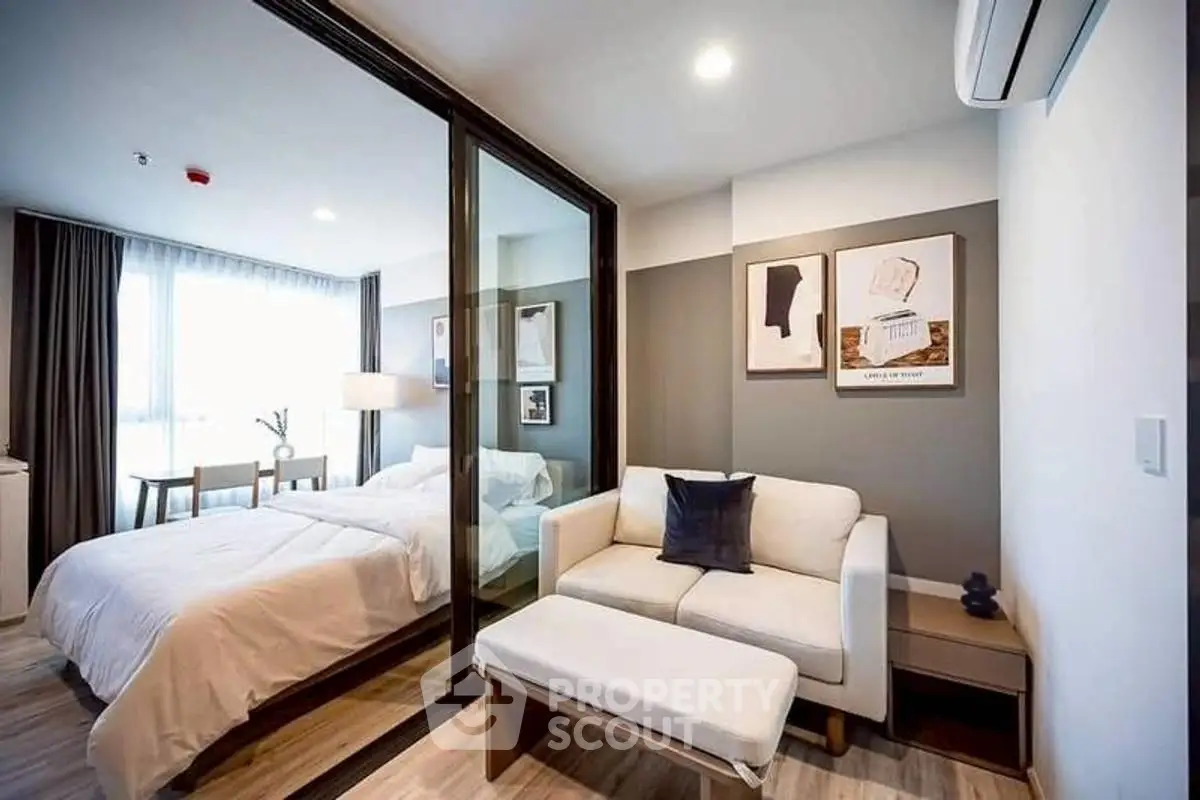 Modern studio apartment with glass partition, cozy living area, and stylish decor.