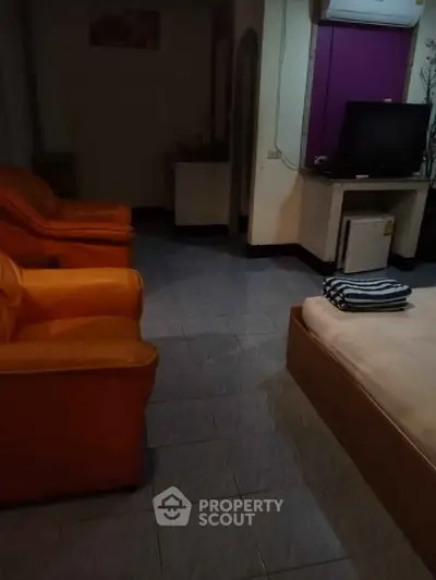 Cozy living room with orange sofas and a TV, perfect for relaxation.