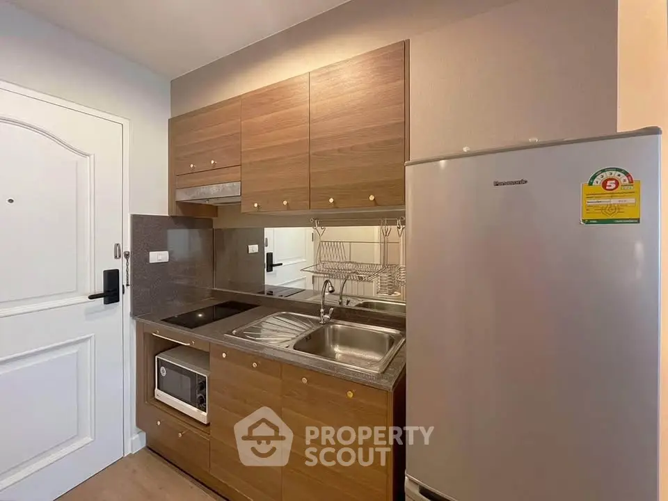 Modern compact kitchen with wooden cabinets and stainless steel appliances