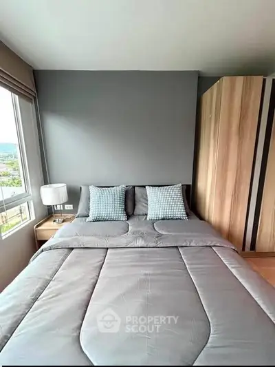 Modern bedroom with stylish decor and large window offering natural light.
