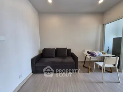 Modern minimalist living room with sleek gray sofa and compact dining area, perfect for urban living.