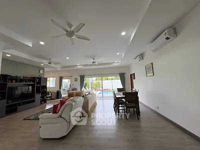 Spacious living room with modern decor and pool view, perfect for family gatherings.