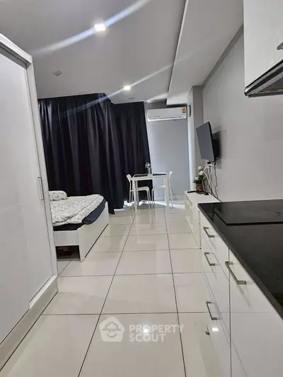 Modern studio apartment with sleek design and ample natural light, featuring a cozy bed and compact dining area.