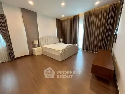 Spacious bedroom with elegant wooden flooring and luxurious curtains