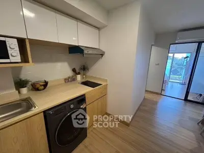 Modern kitchen with sleek appliances and open layout leading to a bright balcony view.