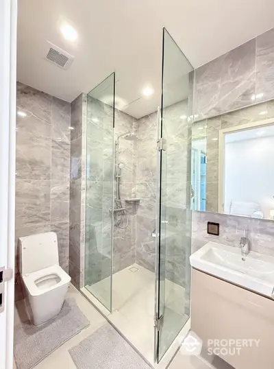 Modern bathroom with glass shower and sleek fixtures in luxury apartment