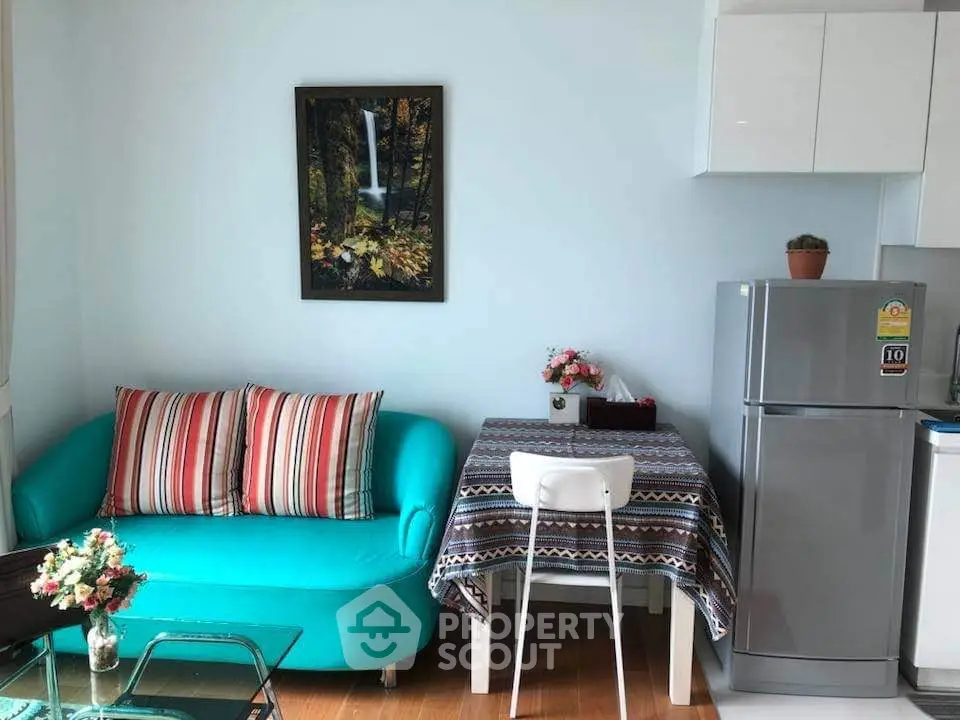 Charming compact living space with vibrant sofa and modern kitchen appliances.