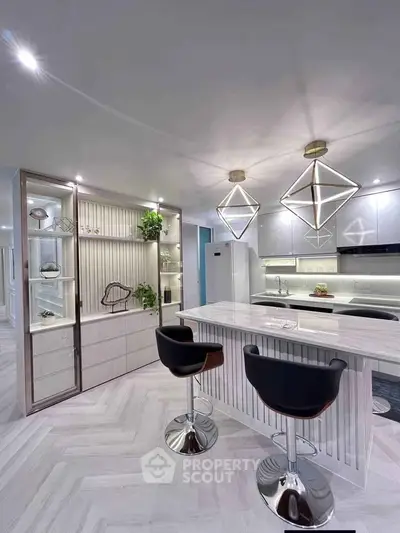 Modern kitchen with sleek design, featuring stylish bar stools and geometric pendant lights.