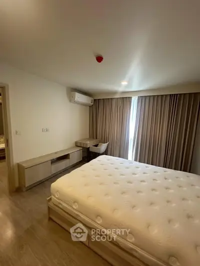 Spacious bedroom with modern furnishings and natural light, featuring a comfortable bed and stylish desk area.