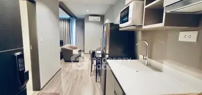 Modern open-layout kitchen with sleek appliances and cozy living area in stylish apartment.