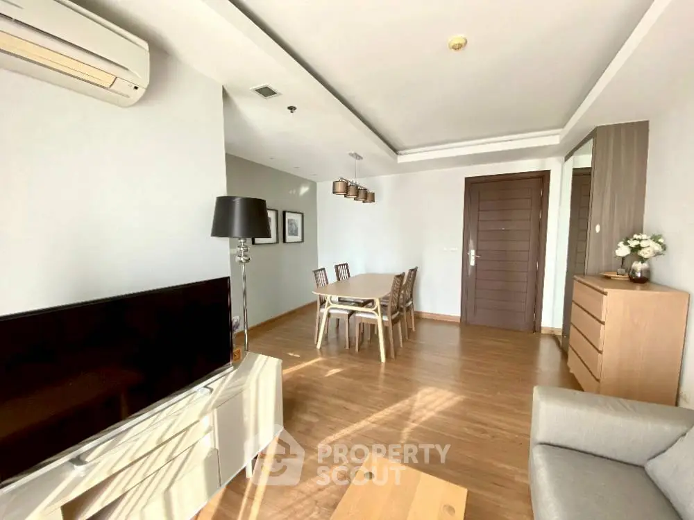 Spacious modern living room with dining area, wooden flooring, and stylish furniture.