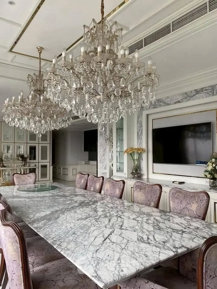 Luxurious dining room with marble table and elegant chandeliers in a sophisticated setting.