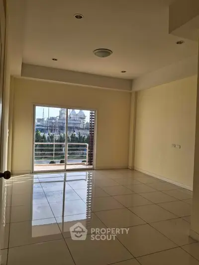 Spacious empty room with large window and tiled flooring, perfect for customization.