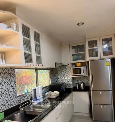 Modern kitchen with sleek cabinets, stainless steel appliances, and mosaic tile backsplash.