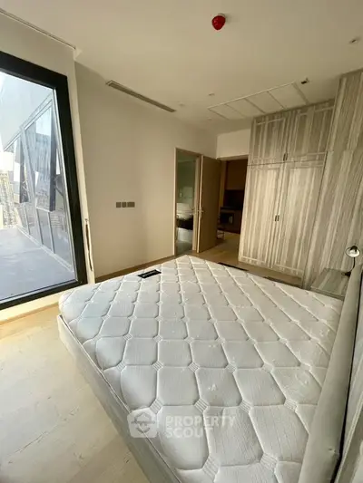 Spacious bedroom with large window and built-in wardrobe in modern apartment