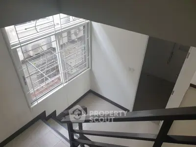 Bright stairwell with large window and modern railing in a residential building.