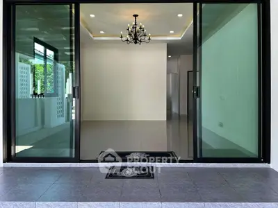 Spacious modern living room with elegant chandelier and large glass doors opening to a serene outdoor area.